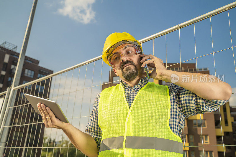 建筑工程师、工人或建筑师在建筑工地打电话