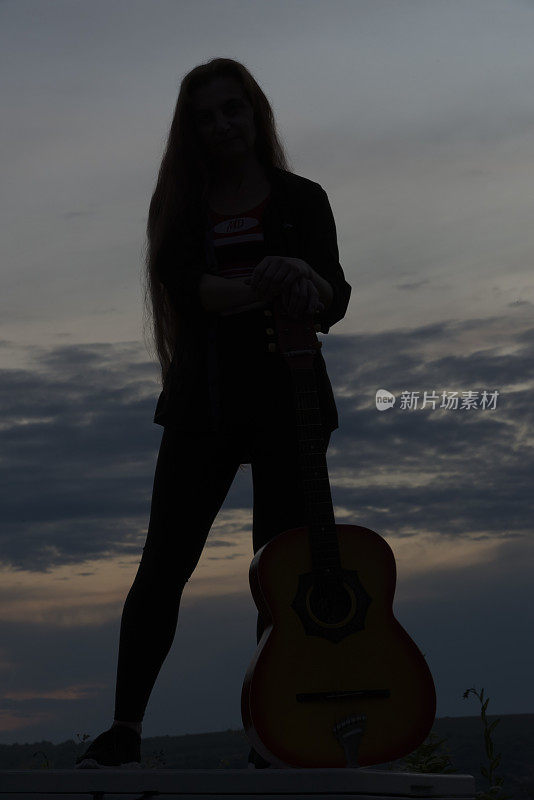 剪影女子在日落弹吉他