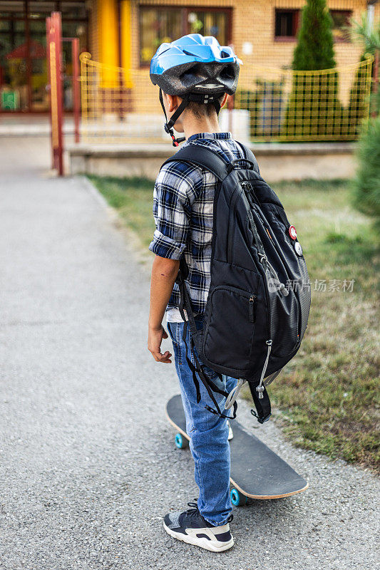 男小学生踩着滑板上学