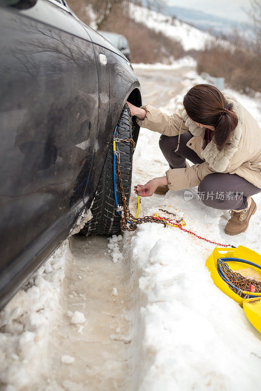 漂亮女人在车上安装雪链