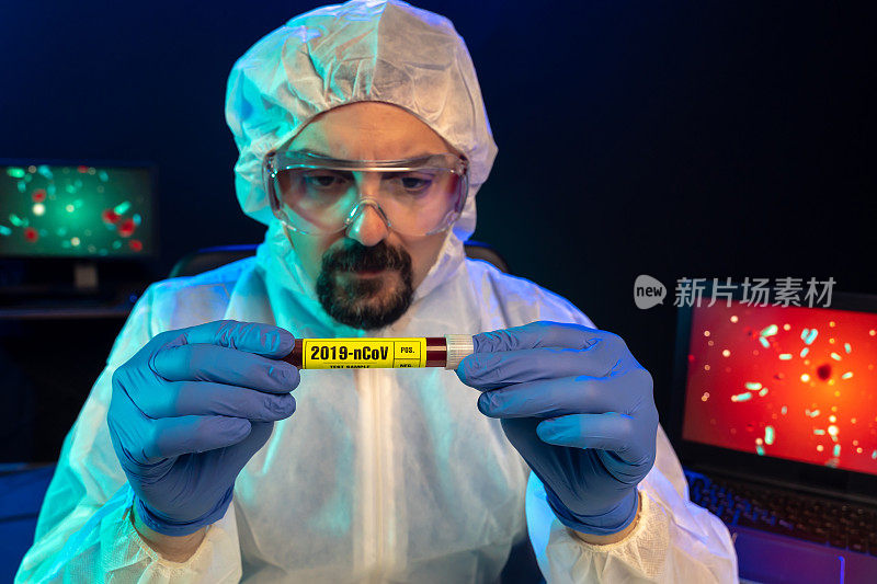 实验室科学家戴着蓝色手术手套和防护眼镜在实验室查看2019-nCoV(冠状病毒，COVID-19)血液样本