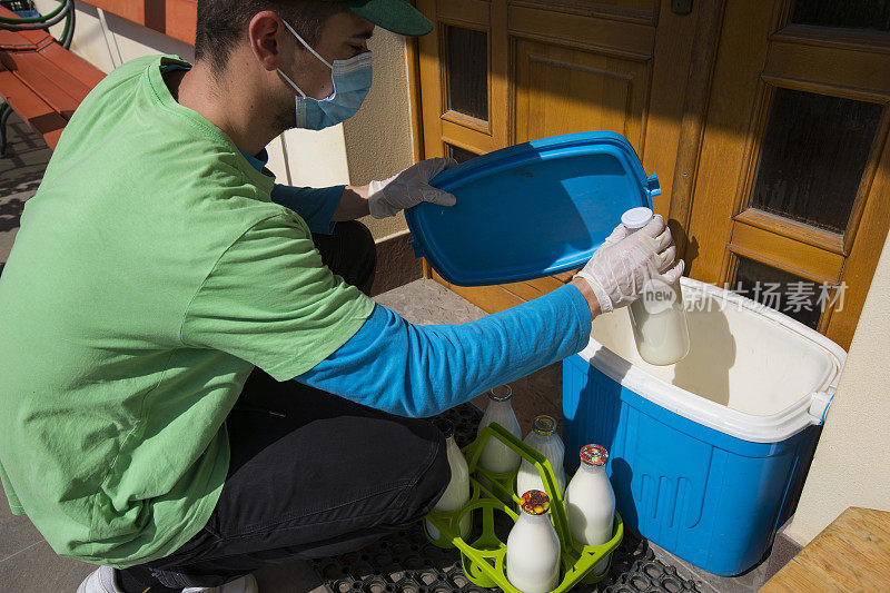 在冠状病毒大流行期间，快递员将牛奶瓶放在冷却容器中放在前门