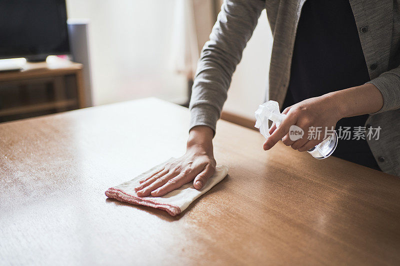 女人用酒精消毒家里的桌子