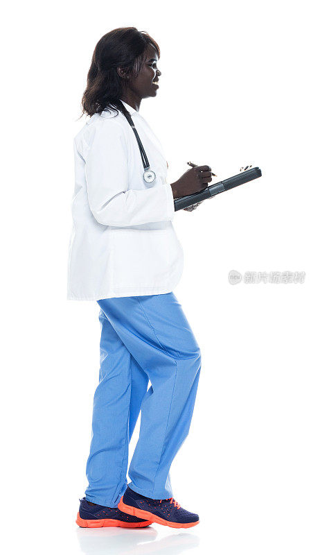 非洲裔年轻女医生走在白种人背景下穿着实验服拿着写字板