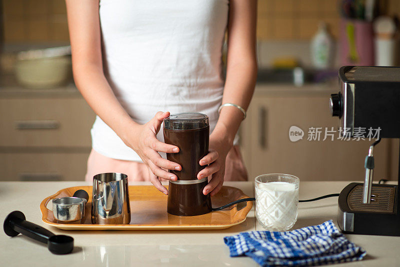 一名妇女在家煮咖啡时用咖啡研磨机磨粉