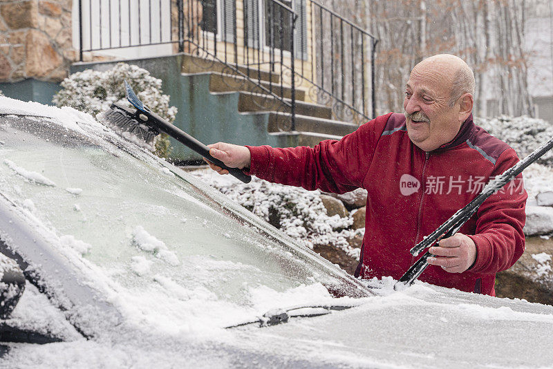 一名老人在一所乡村房屋前清理积雪