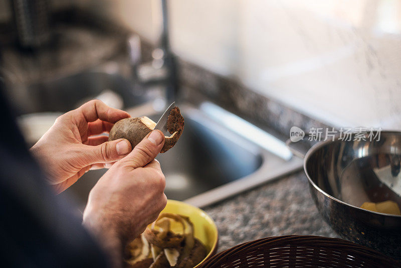 隔离烹饪:一名男子在煮土豆之前剥土豆皮