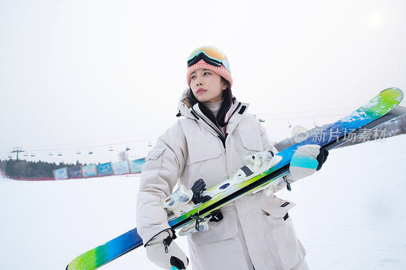 滑雪场上抱着滑雪板看远方的青年女人