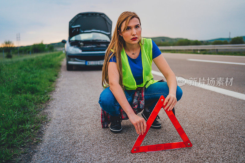 女子用红色三角警示牌保护车辆