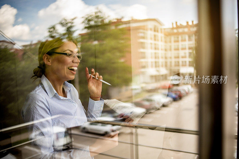 一位女商人站在窗边，一边思考一边谈生意