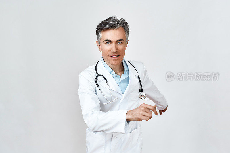 匆匆的帮助。男成熟的医生在医疗制服，听诊器周围的颈部运行在工作室的灰色背景，看着相机