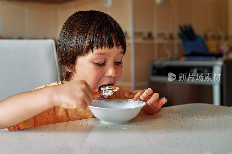 4-5岁可爱的孩子早餐吃玉米片加牛奶。