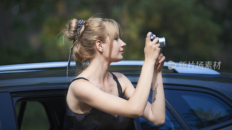 一名年轻女子在公路旅行中使用相机