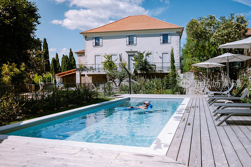 在法国阿尔代什有木制甲板和游泳池的法国度假屋。在法国南部的度假屋豪华度假期间，女人放松与木制甲板的游泳池