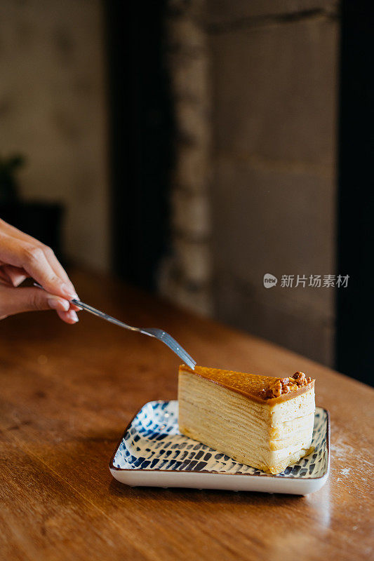 一个女人在咖啡馆用叉子吃薄饼