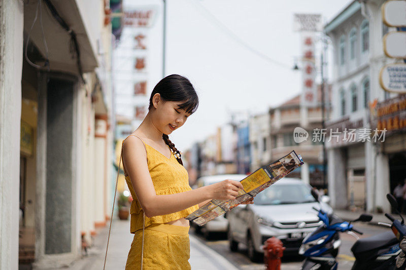 年轻的亚洲女性游客探索街道与地图在手