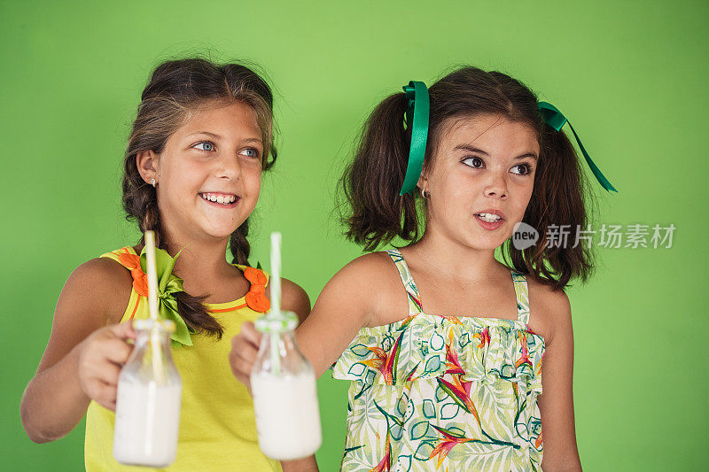 两个女孩拿着可重复使用的牛奶瓶
