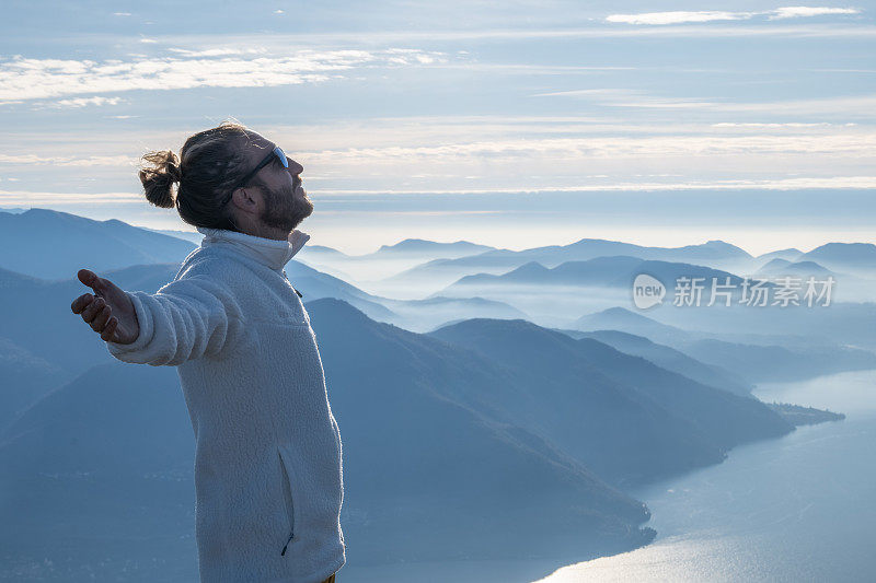 一个徒步旅行者双臂伸开站在山顶上