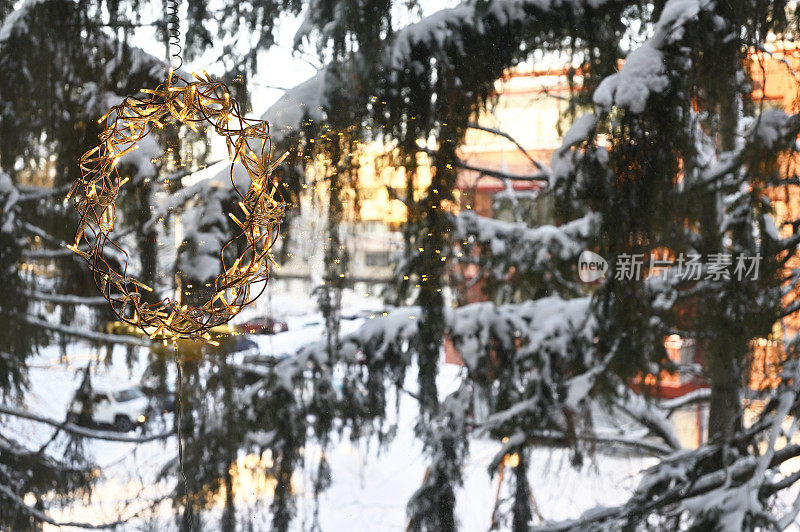 圣诞的花环挂在窗户上，雪花覆盖着冷杉树