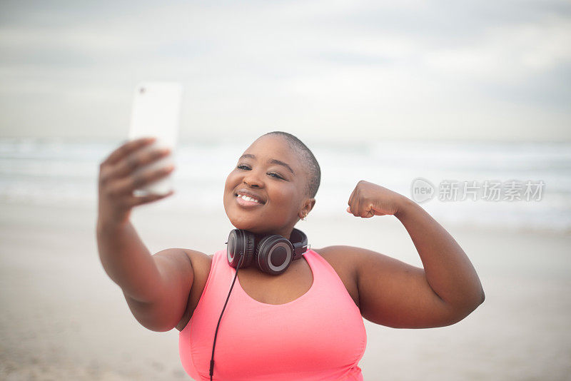 自拍，强壮的大码黑人女性早上在海滩健身或做有氧运动。微笑，锻炼或运动和快乐的年轻跑步者或运动员弯曲手臂肌肉的训练或锻炼