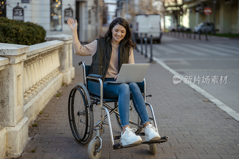 坐在轮椅上的残疾妇女在城市街进行视频通话