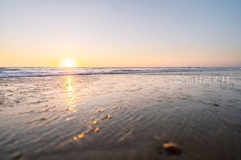 原始的日落海滩与发光的地平线和平静的大海