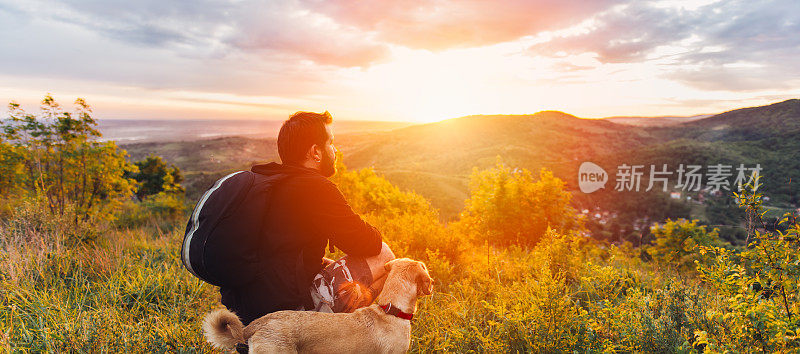 一个人带着狗欣赏山上的日落
