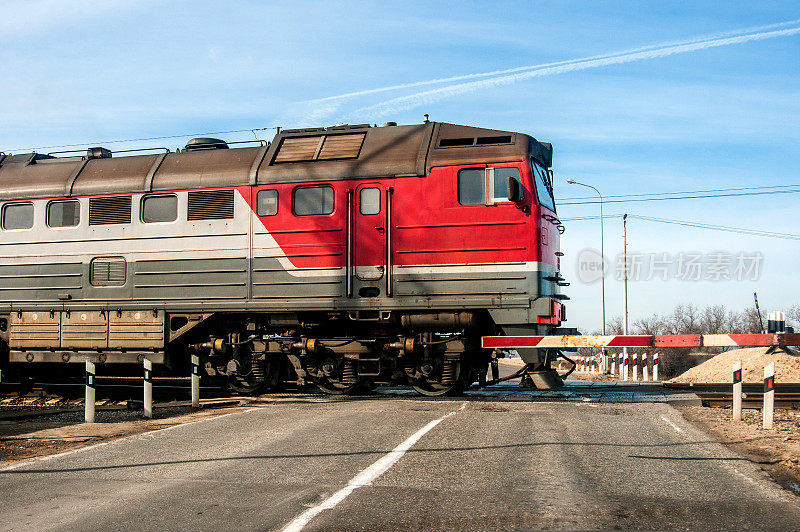 在一条小路上，一列古老的俄罗斯红色火车正穿过一个平道口。