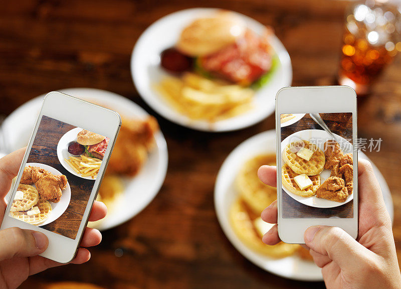 两个朋友正在用智能手机给他们的食物拍照