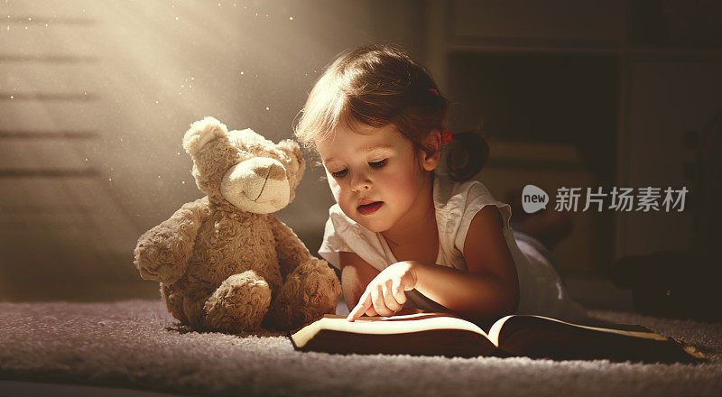 一个小女孩在黑暗的家里读一本魔法书