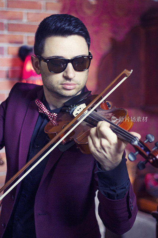 年轻有魅力的男子用表情拉他的小提琴