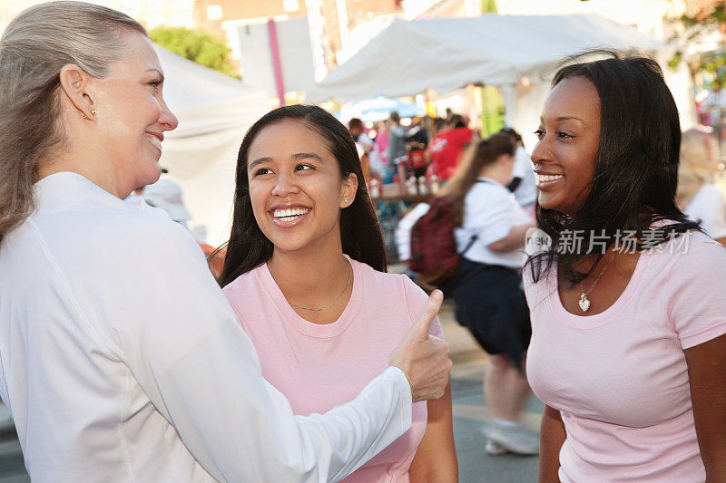 妇女在乳腺癌集会上向朋友们竖起大拇指