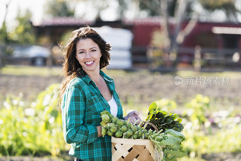 在有机农场的妇女提着一篮子蔬菜