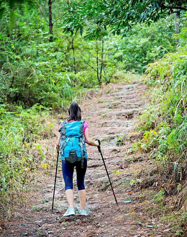 在树林里背着背包的年轻女性徒步旅行者