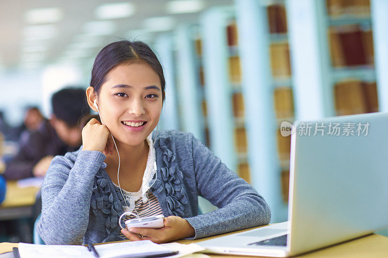 年轻漂亮的亚洲大学生在图书馆学习