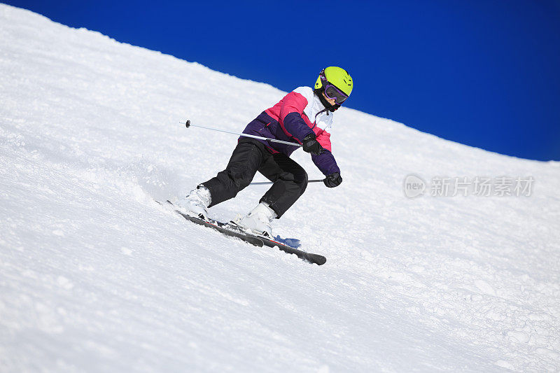 女孩滑雪者滑雪雕刻在阳光明媚的滑雪胜地