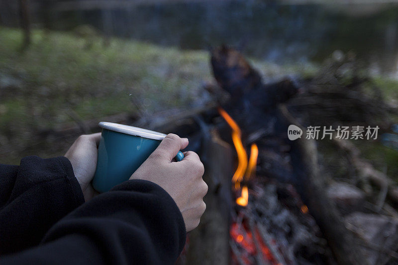 旅行者在篝火前拿着蓝色的杯子