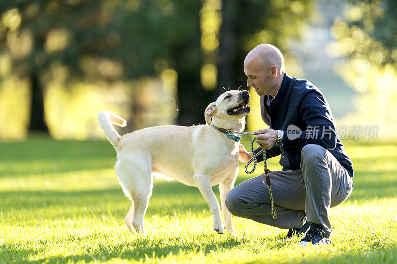 成年男性在公园里抚摸他快乐的宠物狗