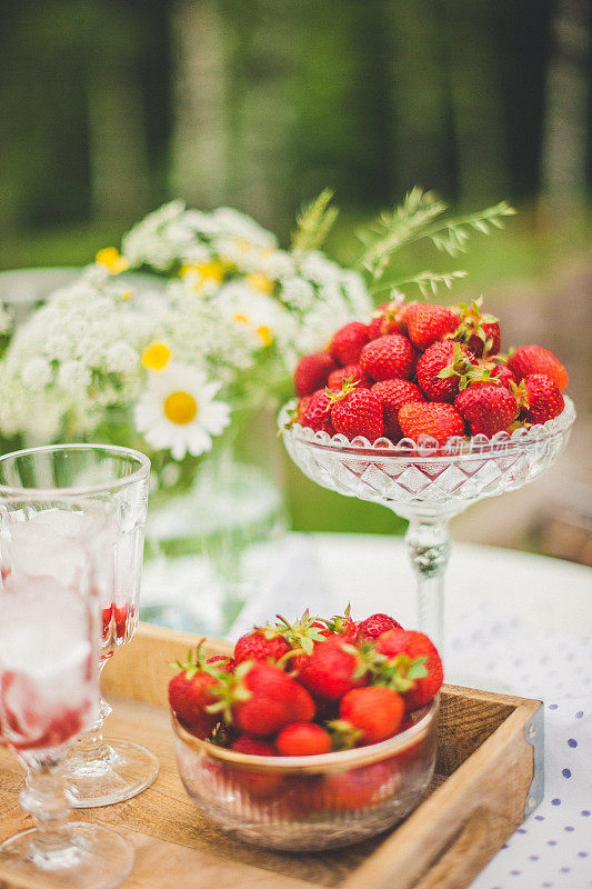 夏天的草莓和鸡尾酒在花园里的桌子上