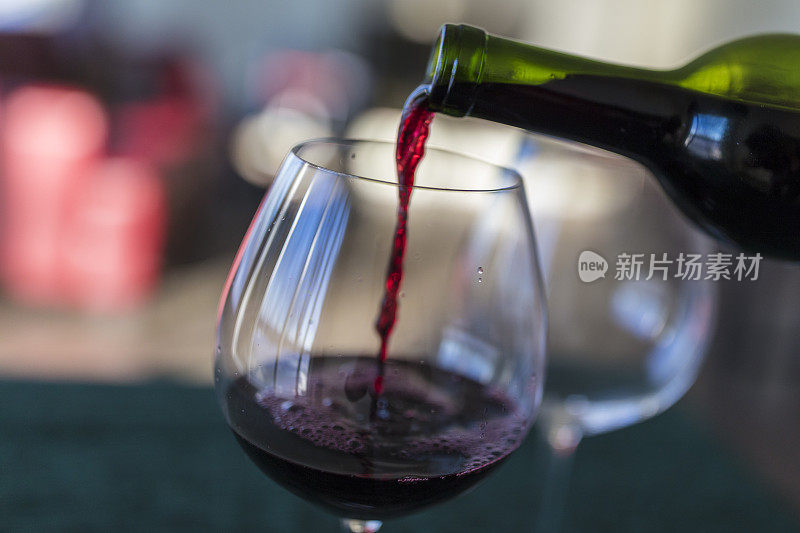 特写红酒被倒入从一个瓶子到玻璃杯。