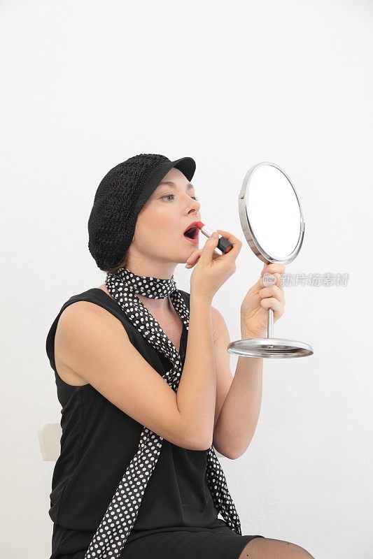 复古风格的女人是看着镜子，涂着嘴唇。