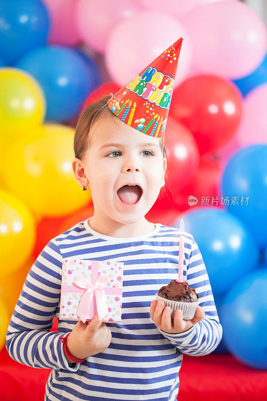 快乐的3岁女孩拿着生日蛋糕和礼物