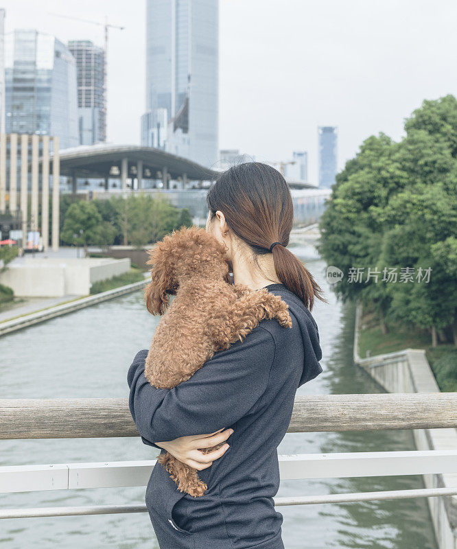 一个女人抱着她的宠物站在桥上看风景