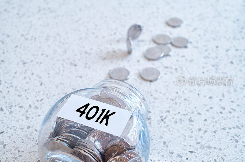 401k退休计划概念与一个玻璃罐满硬币在大理石台面上