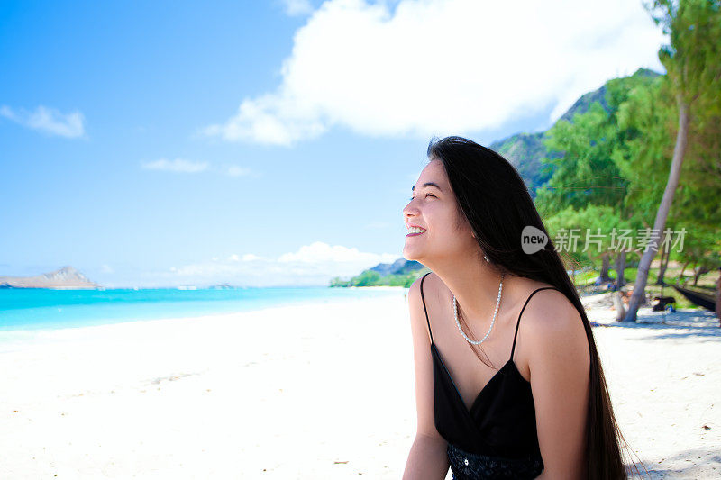 混血少女坐在夏威夷海滩，侧面，微笑