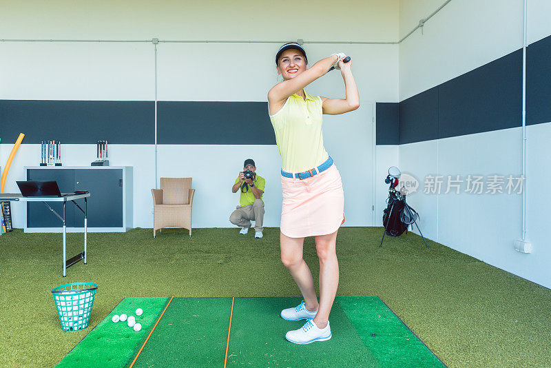 健身妇女在室内专业课上练习高尔夫挥杆
