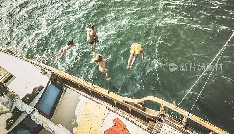 鸟瞰图上的年轻人从海上旅行的帆船上跳下来-富有快乐的朋友在夏天的帆船派对日有乐趣-独家豪华度假概念-复古对比去饱和滤镜