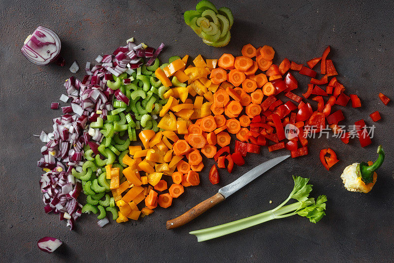 平铺健康素食为背景。切片的新鲜蔬菜在深色的背景。俯视图