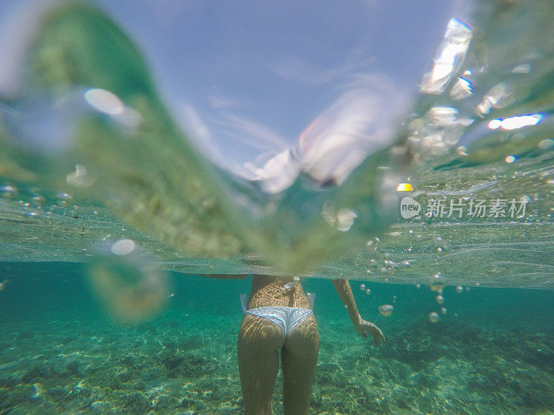 水下拍摄的年轻女子站在热带清澈的海水中度假的人的概念