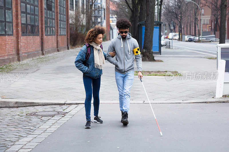 一名妇女在过马路时帮助盲人